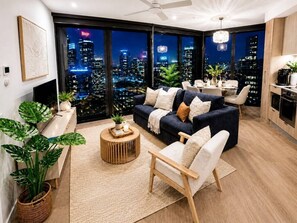 Ein modernes Wohnzimmer mit Stadtblick, inklusive Sofa, Sessel, Couchtisch und Essbereich.