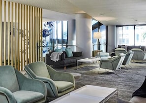 Eine moderne Hotellobby mit Sitzbereichen, einem großen Fenster und einer Wandverzierung.