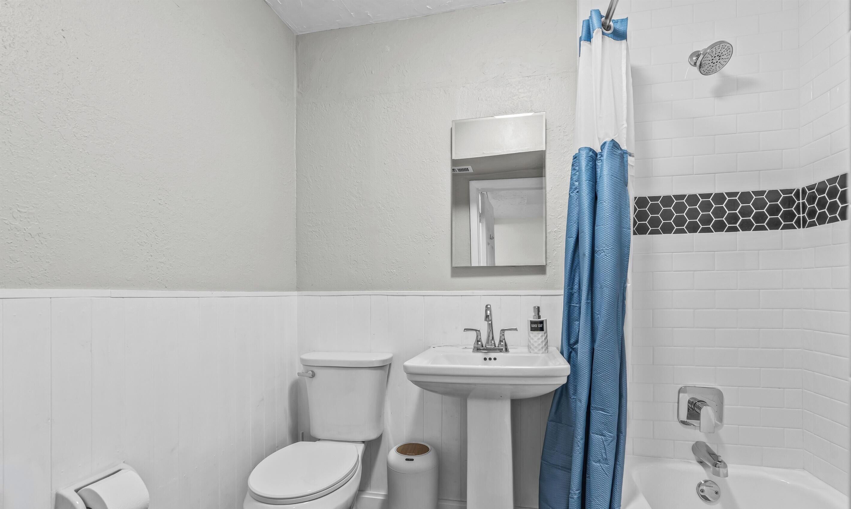 A bathroom with a toilet, sink, and shower.