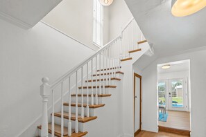 Eine Treppe mit weißen Geländern und Holzstufen, die zu einer Tür führen.