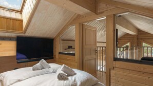 Una habitación de cabaña de madera con una cama, un televisor de pantalla plana y un balcón.