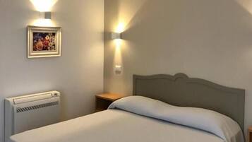 A bedroom with a bed, a radiator, a nightstand, and two wall-mounted lights.