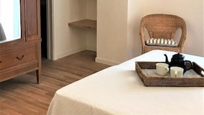 A room with a wooden cabinet, a wicker chair, a white table with a tray, and built-in shelves.