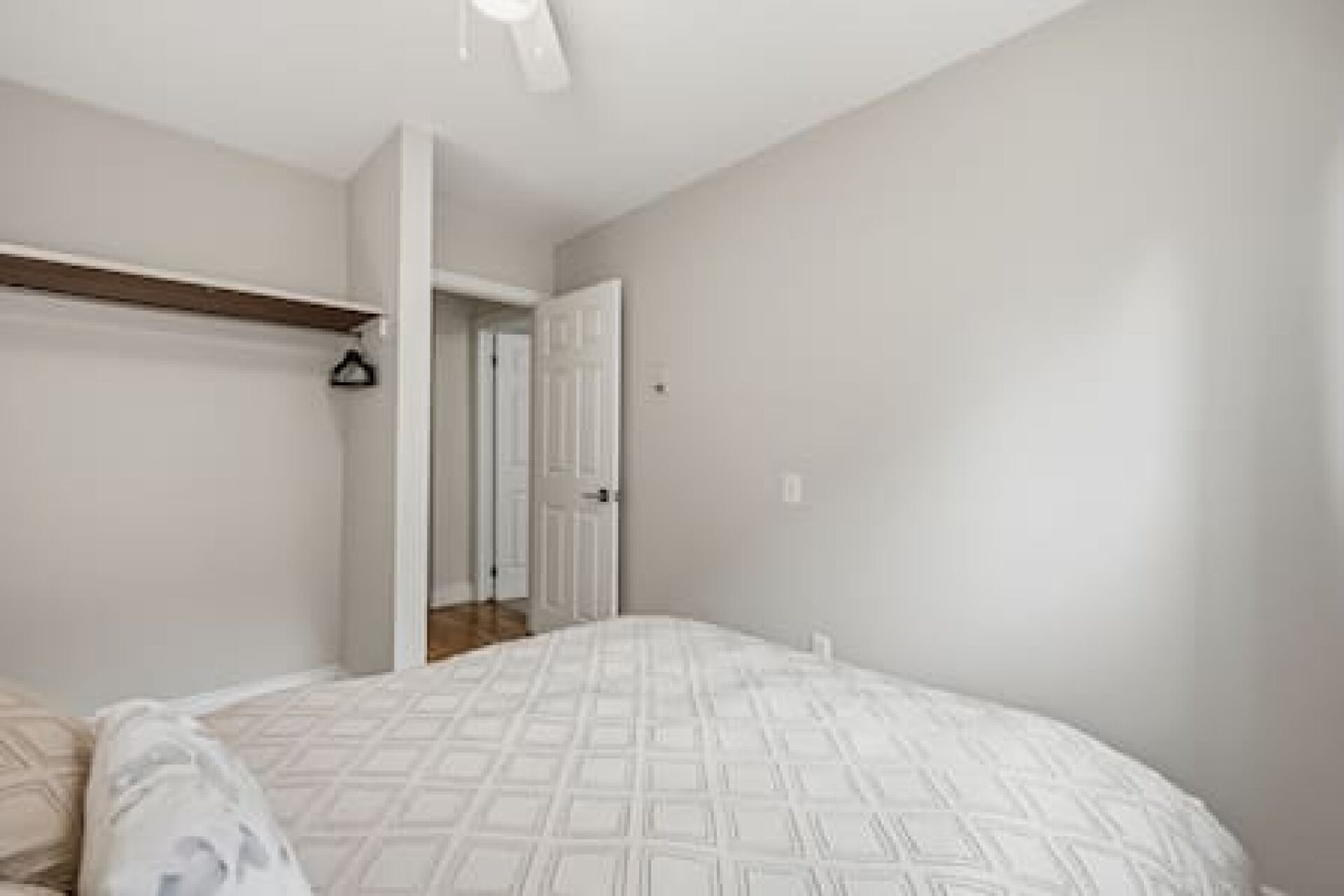 A bedroom with a bed, a wardrobe, and a door leading to another room.