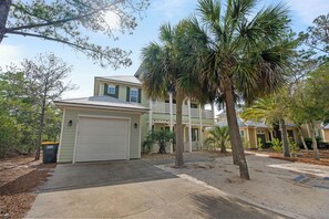 Ein Wohnhaus mit Garage, einer Veranda und einer Palme.