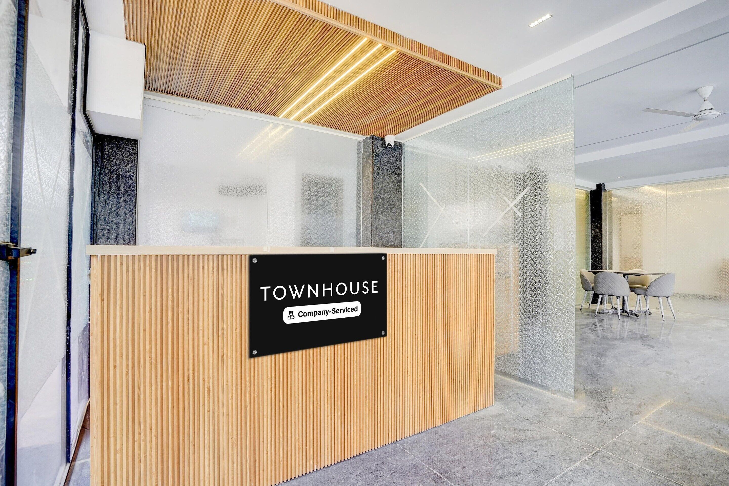 A reception area with a wooden counter, a sign reading 'TOWNHOUSE Company-Serviced,' and a glass partition.