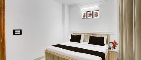 A bedroom with a bed, bedside table, and a wall-mounted light fixture.