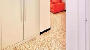 Una habitación con un armario, un sofá rojo y una alfombra estampada.