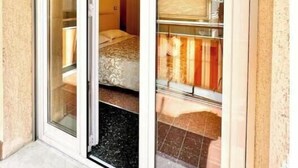 Una habitación de hotel con una puerta corrediza de vidrio, una cama y un pequeño vestíbulo.