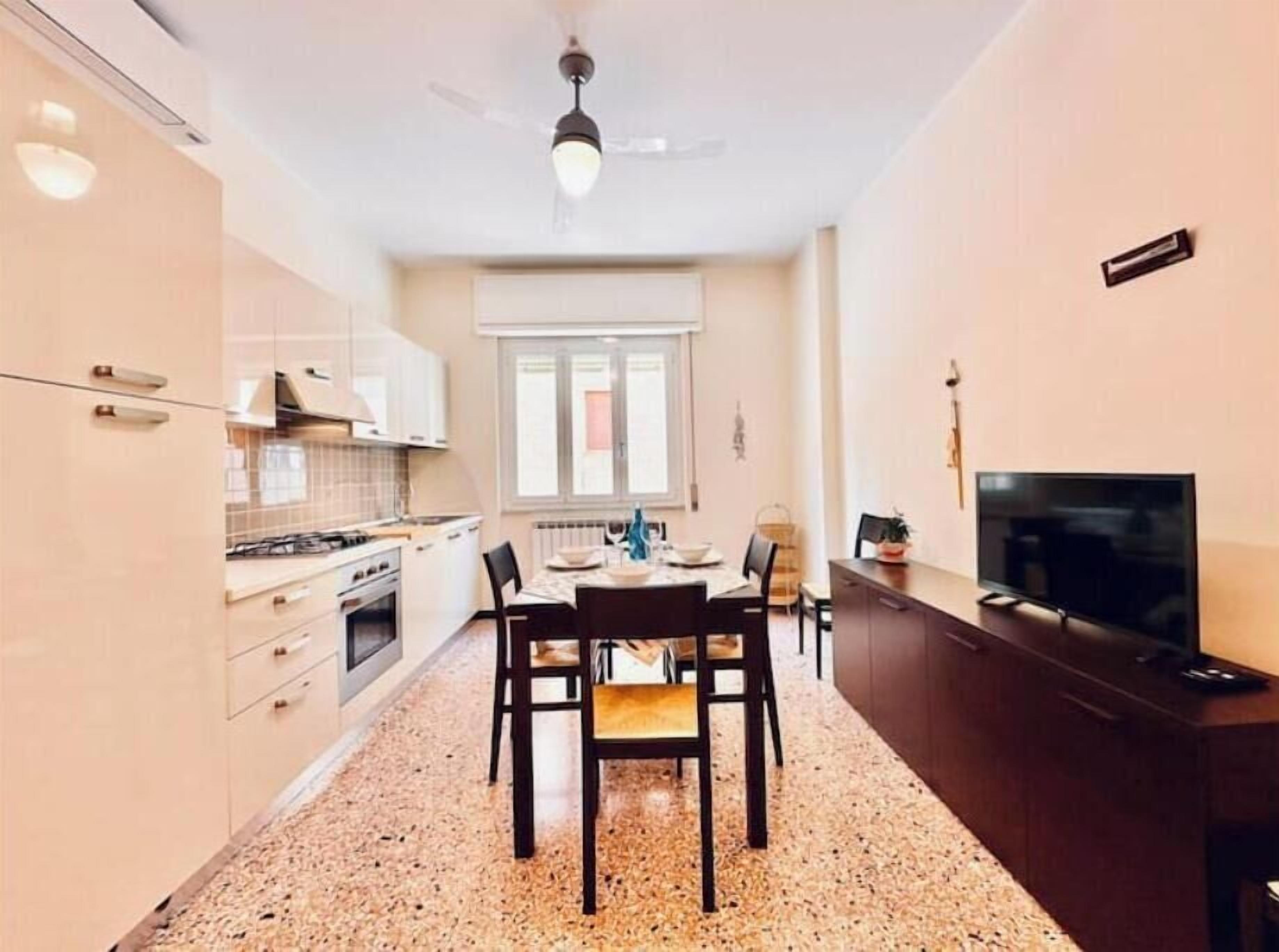 A compact kitchen with a dining area, a TV, and a ceiling fan.