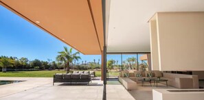 Ein moderner Außenbereich mit Pool, Sitzgelegenheiten und Blick auf die Landschaft.