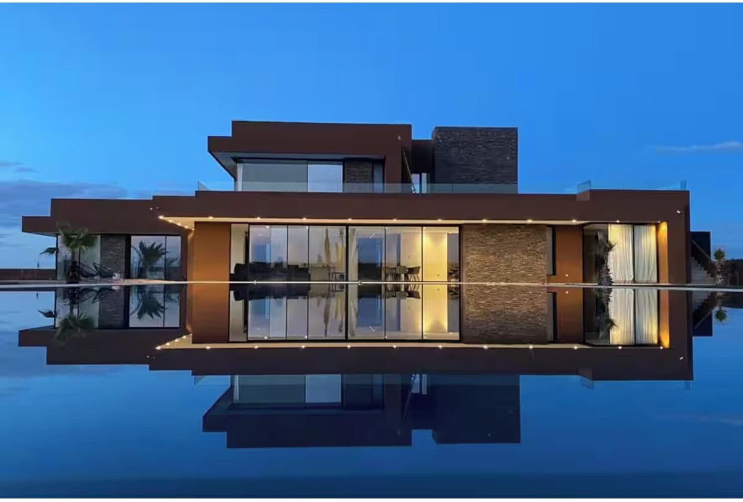 A modern building with a reflective pool in front, large windows, and a flat roof.
