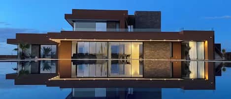 A modern building with a reflective pool in front, large windows, and a flat roof.