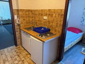 A compact kitchenette with a sink, stove, and storage drawers.
