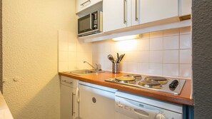 Eine kleine Küche mit Mikrowelle, Herd, Spüle und Geschirrspüler.