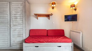 Ein Schlafzimmer mit Bett, Fernseher, Regal und Wandleuchten.