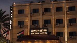 Un bâtiment d’hôtel avec une enseigne indiquant « Siveen Hotel » et des drapeaux.