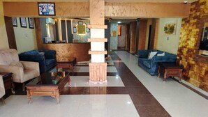 Un hall d’hôtel comprenant un comptoir d’accueil, un espace salon et une colonne décorative.