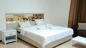 Une chambre d’hôtel comprenant un lit, une table de chevet, une table basse et une tête de lit décorative.