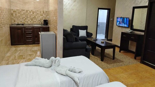 Une chambre d’hôtel équipée d’un lit, d’un canapé, d’un bureau, d’une télévision et d’une kitchenette.