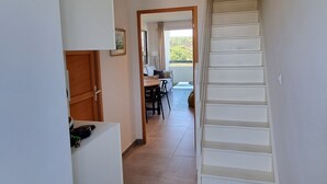 En smal hall som leder till ett matområde med en trappa.