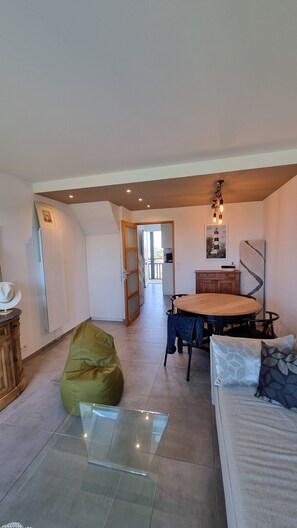 A spacious loft with a dining area, a bean bag, a glass table, and a view of the outside. - At the gates of Biarritz, swimming pool, tennis court, golf course, children's playground, beaches within walking distance (Bidart)