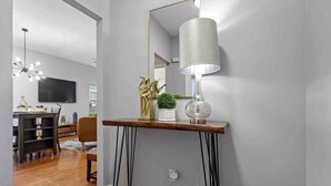 Un moderno salón con una consola de madera, una lámpara de pie y un televisor montado en la pared.