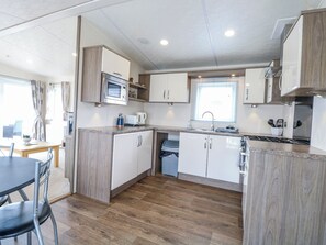 A compact kitchen with a microwave, coffee maker, and sink. - 59 Cliff Field (Lowestoft)