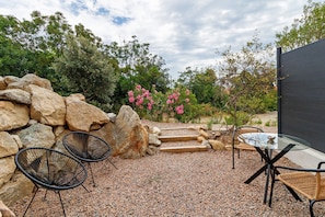 An outdoor seating area with a table and chairs, surrounded by rocks and plants.