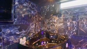 A modern bathroom with a large, dark-colored jacuzzi tub, marble walls, and a ceiling light. - Bed and Breakfast 'Luxurious Love Room By Vill'amore' with Private Terrace, Wi-Fi and Air Conditioning (Solaro)