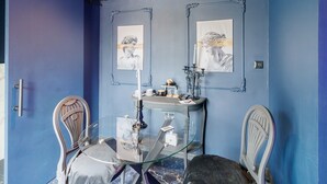 A room with a glass table, two chairs, a blue wall, and two framed pictures. - Bed and Breakfast 'Luxurious Love Room By Vill'amore' with Private Terrace, Wi-Fi and Air Conditioning (Solaro)