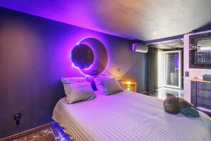 A bedroom with a bed, pillows, a bedside lamp, and a window.