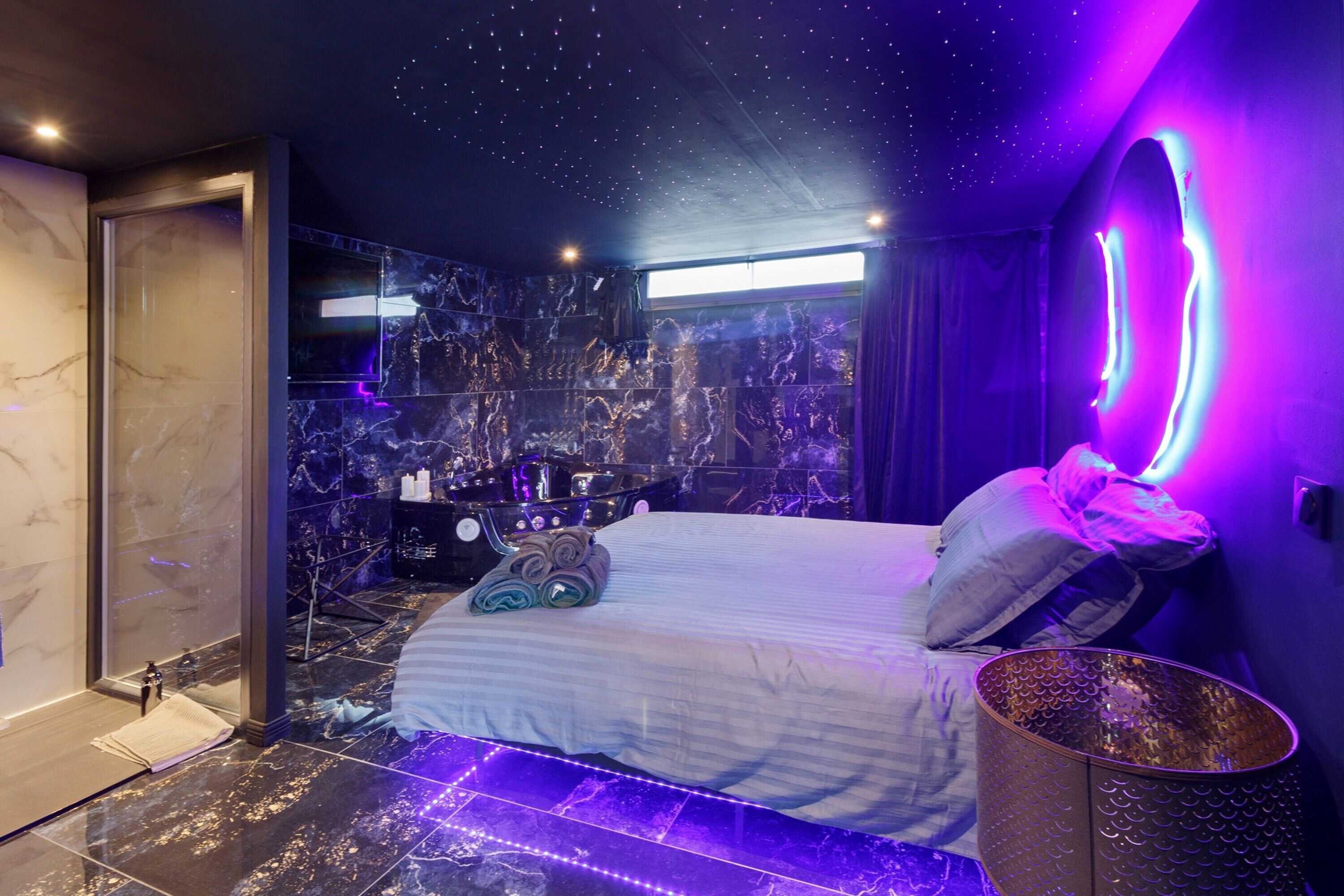 Ein modernes Schlafzimmer mit Bett, Schminktisch und Spiegel sowie einer Sternenhimmel-Decke.