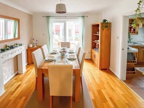 Ein Essbereich mit einem Holztisch, gedeckt für vier Personen, einem weißen Kamin und Blick durch das Fenster.