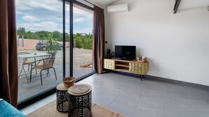 A modern living room with a TV, a dining area with a table and chairs, and a sliding glass door leading to an outdoor space. - Bed and Breakfast 'Vill'amore' with Sea View, Wi-Fi and Air Conditioning (Solaro)