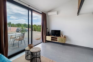 A modern living room with a TV, a dining area with a table and chairs, and a sliding glass door leading to an outdoor space. - Bed and Breakfast 'Vill'amore' with Sea View, Wi-Fi and Air Conditioning (Solaro)