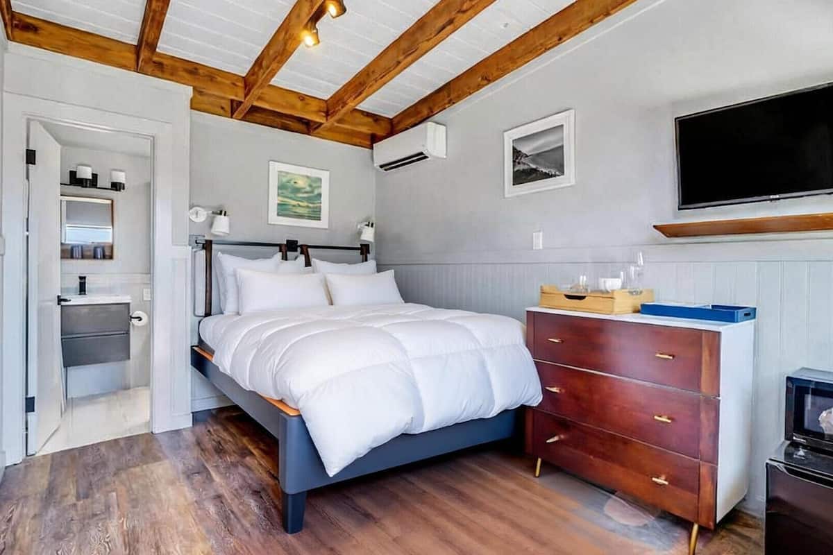 Une chambre à coucher avec un lit, une commode, une télévision et des œuvres d’art accrochées au mur.