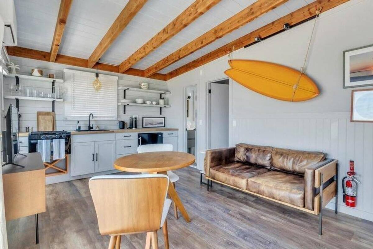 Une cuisine moderne avec des meubles blancs, une table à manger en bois et un canapé en cuir.