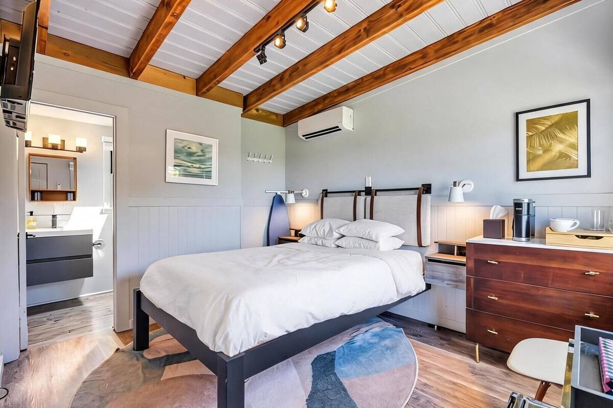 Une chambre à coucher avec un lit, une commode, une table de chevet et une fenêtre.