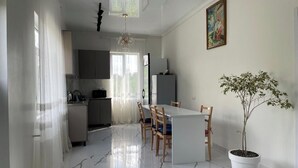 Una cocina moderna con zona de comedor, una planta en maceta y un cuadro en la pared.