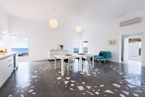 Ein modernes Interieur mit Essbereich, weißen Möbeln und Meerblick.