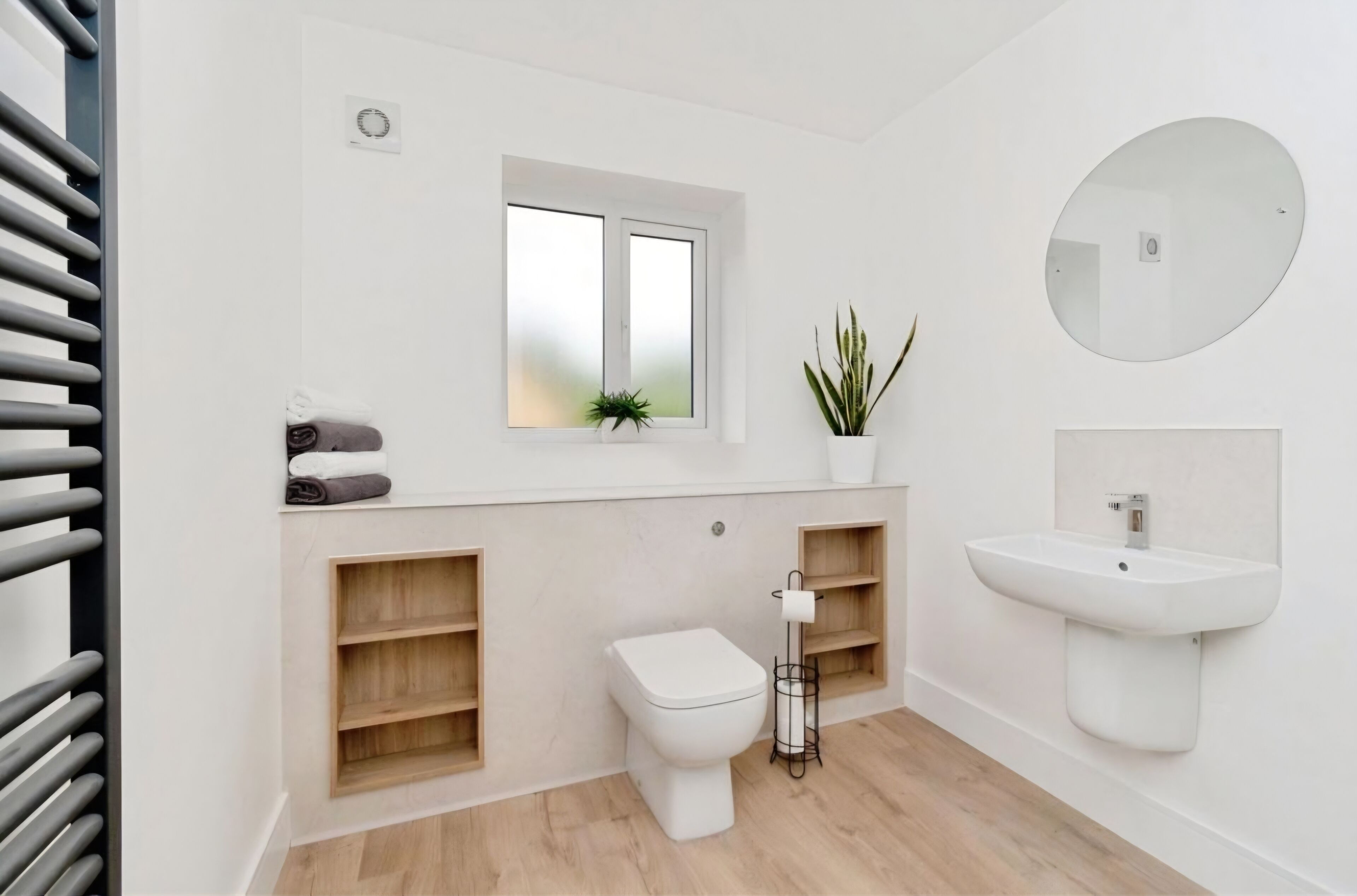 Ein modernes Badezimmer mit Toilette, Waschbecken und Fenster.
