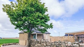 A house with a stone wall, a tree, and a fenced area. - The Bothy in Fraserburgh (Fraserburgh)