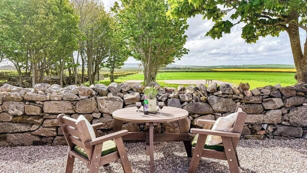 A stone wall, two wooden chairs, a round table, and a bottle of wine. - The Bothy in Fraserburgh (Fraserburgh)