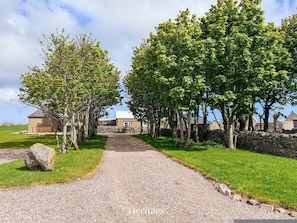 A gravel path leading to a stone wall and buildings with a clear sky. - The Bothy in Fraserburgh (Fraserburgh)