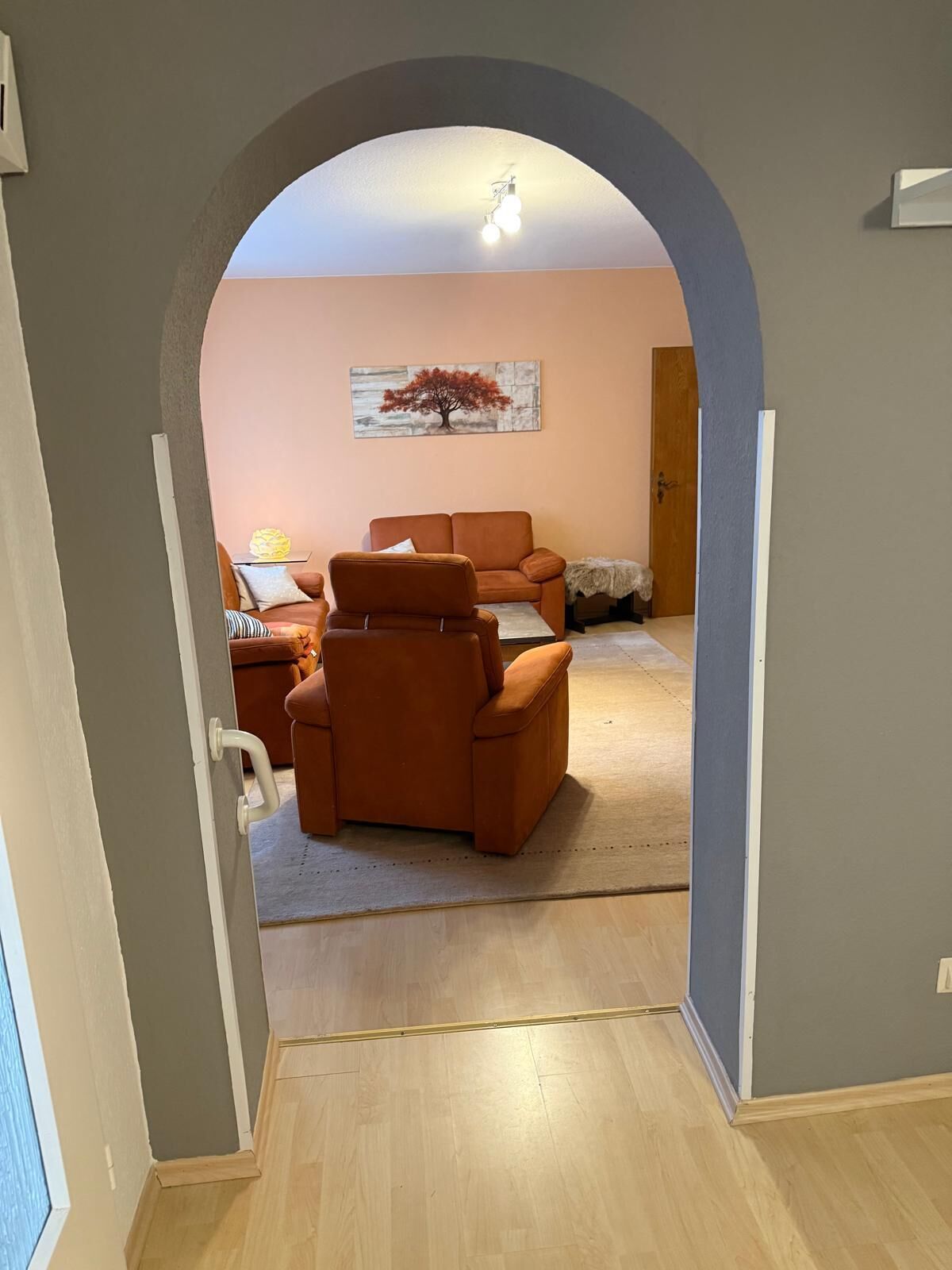 Un salon avec un canapé, un fauteuil et un tableau accroché au mur.