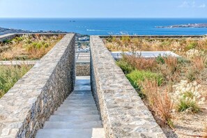 A stone pathway leading to a coastal view. - Villa Pétra - Hidden treasure (Kakapetra)