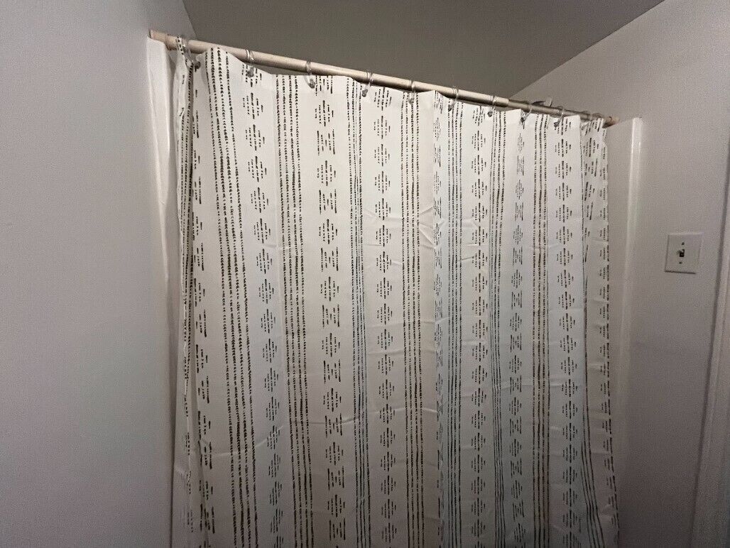 A bathroom with a shower curtain featuring a pattern of text and symbols.