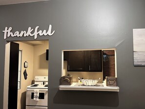 Eine Küche mit dunklen Schränken, einer weißen Arbeitsplatte und einem Schild mit der Aufschrift 'thankful'.