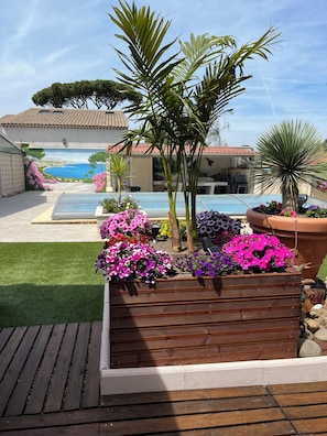 Ein Poolbereich mit Wandmalerei, Holzterrasse und Blumenkästen.